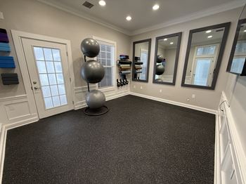 A room with a black floor and a large grey ball on a black stand.